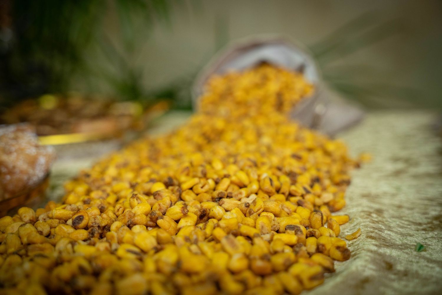 Close-up of vibrant yellow corn kernels scattered on a textured surface.