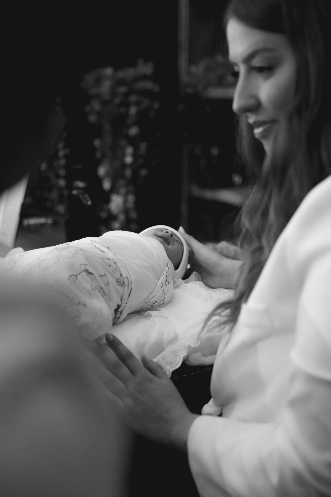 A tender black and white moment showing someone gently holding a baby.