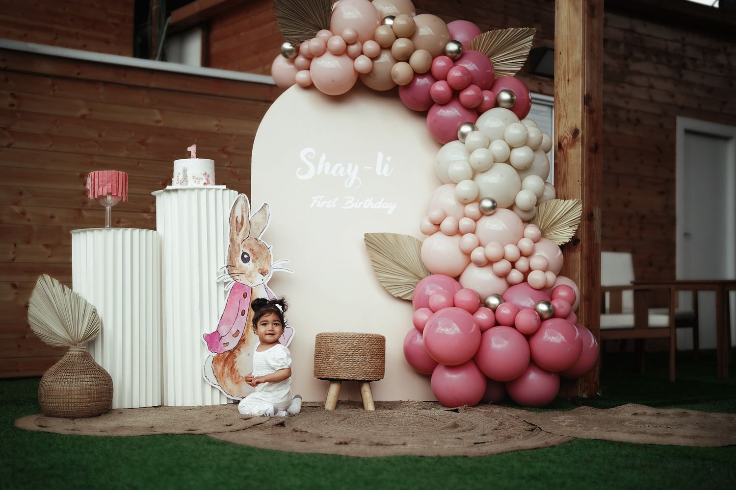 Pink and white balloon arch decoration with party setup outdoors.