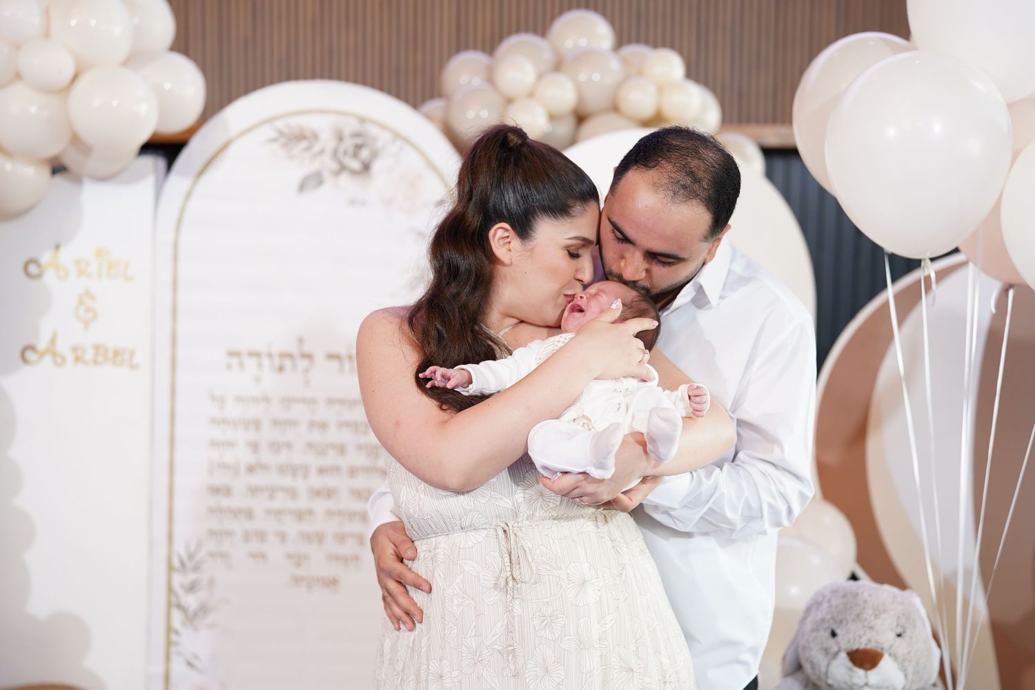 Romantic celebration with white balloon arch and decorative backdrop.