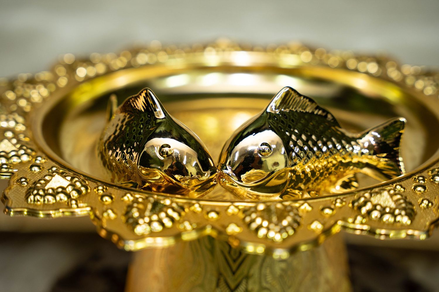 Detailed macro shot of ornate gold wedding bands with intricate fish scale patterns.
