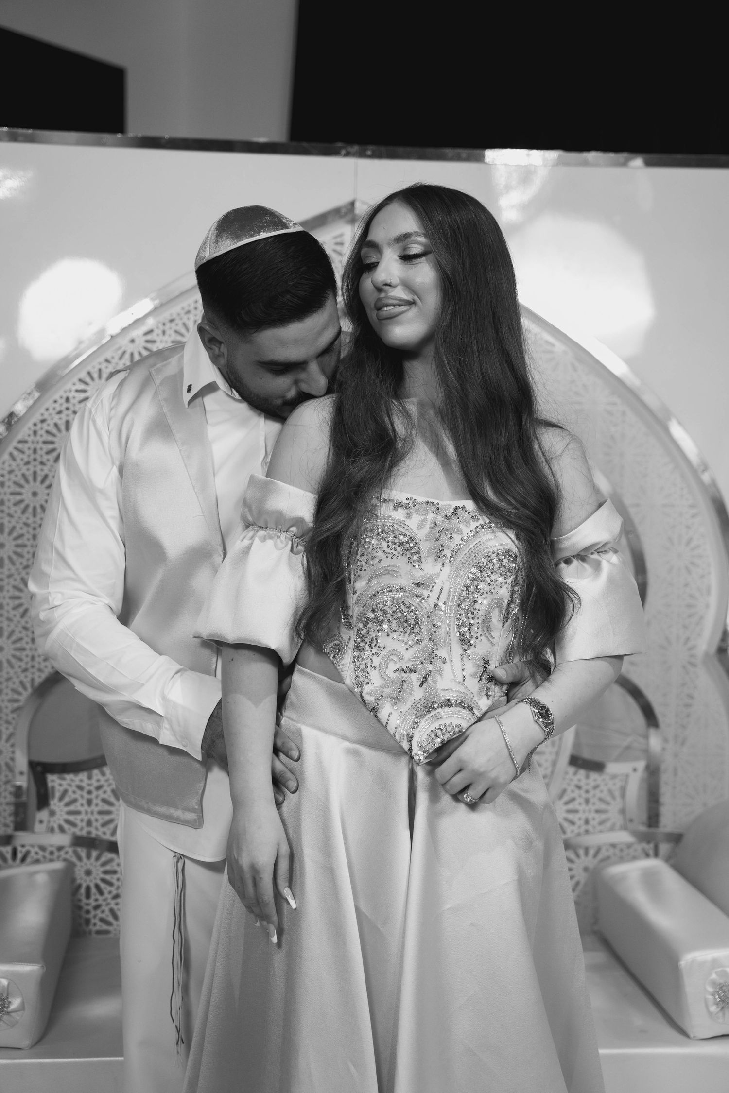 A romantic black and white photo series showing a couple in white outfits embracing and sharing intimate moments.
