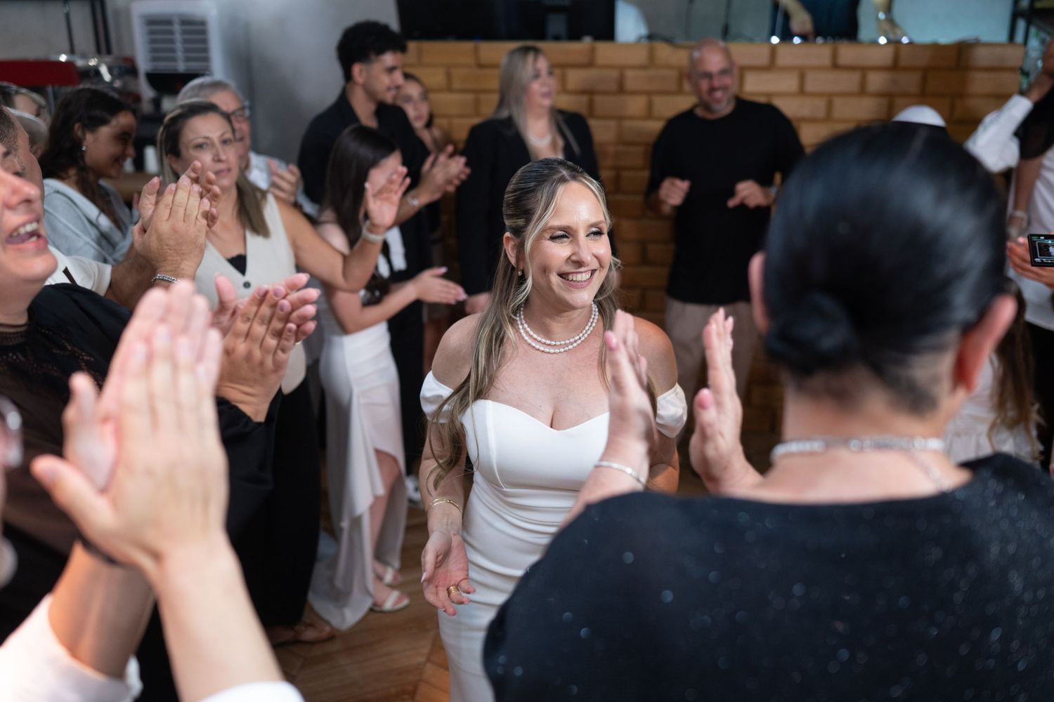 Crowd celebrates at indoor event with hands raised in excitement.