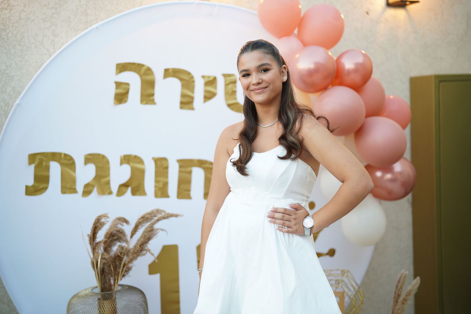 Elegant party setting with peach balloons and gold text decorations on white wall.