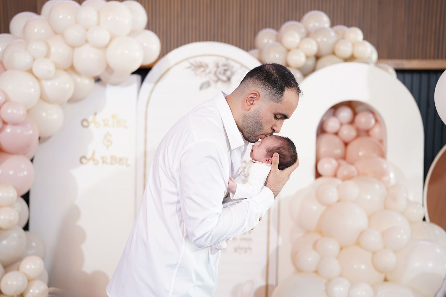 Romantic wedding portraits with soft pink balloon arch and white decor.