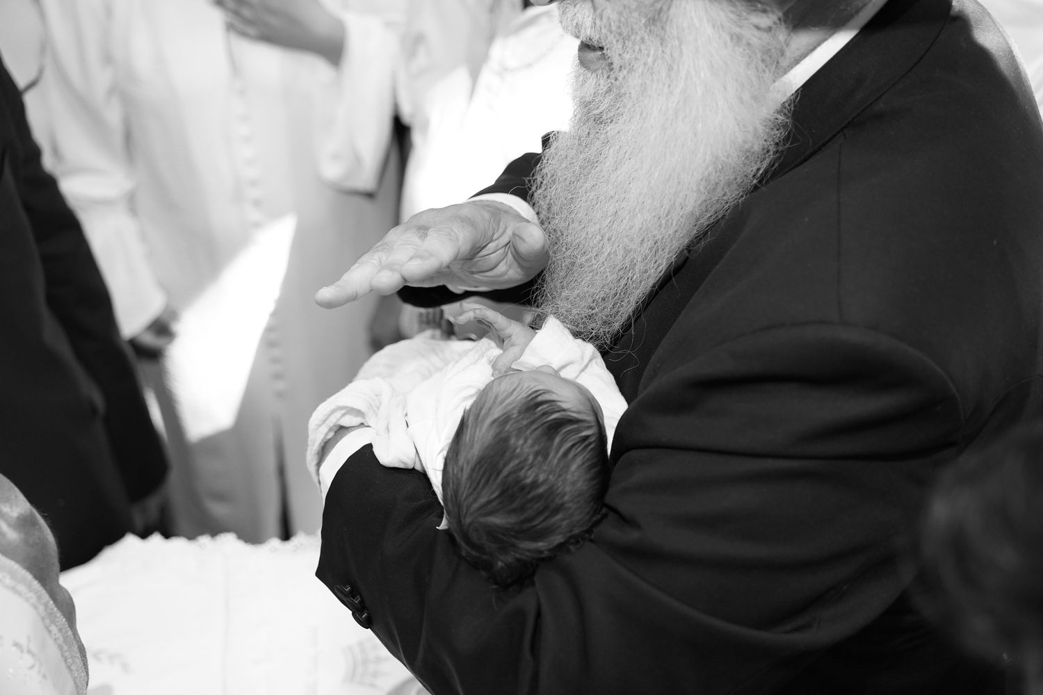 Black and white photo of a baby being held during a religious ceremony.