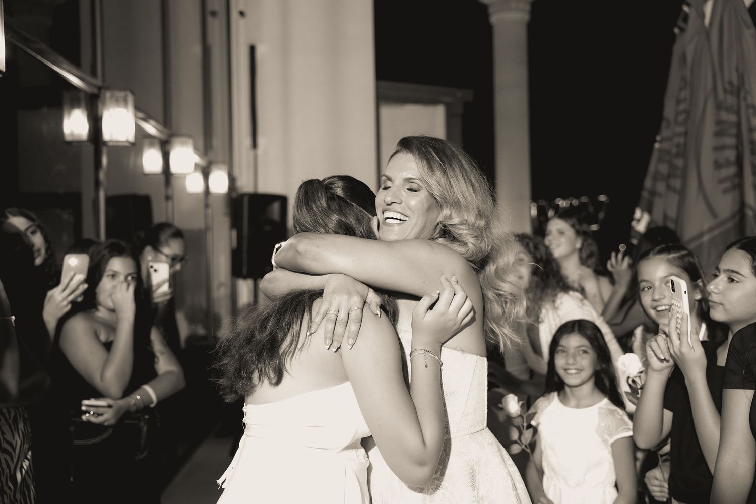 People dancing and celebrating at a lively party with white decor and festive atmosphere.