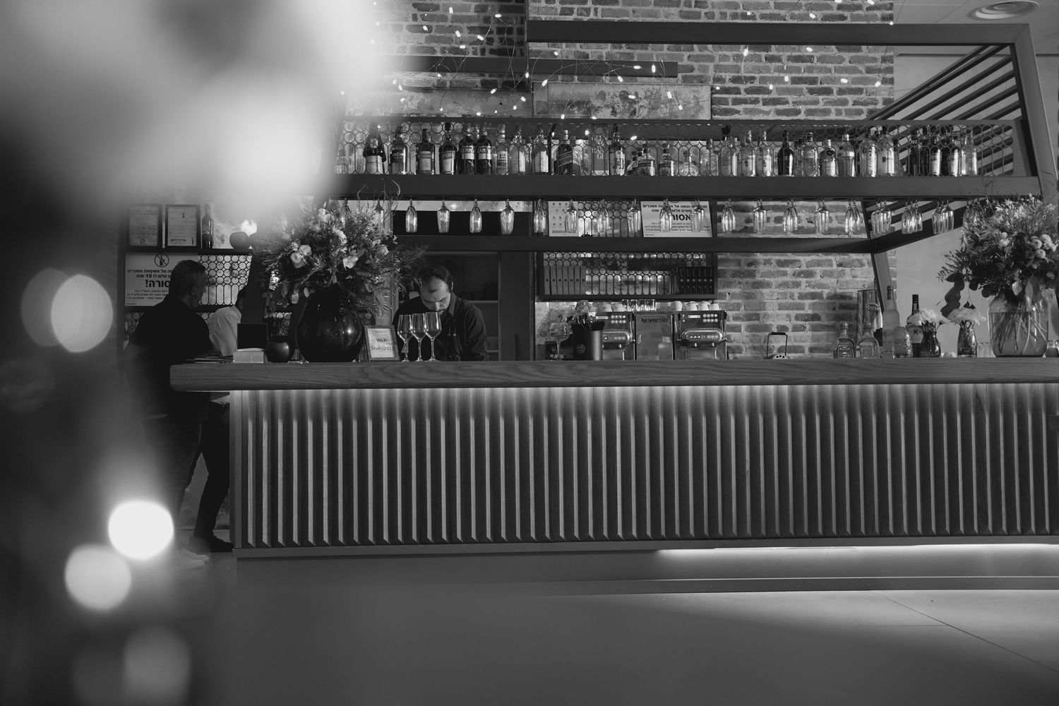 Blurred bar counter with bottles displayed in a dimly lit restaurant setting.