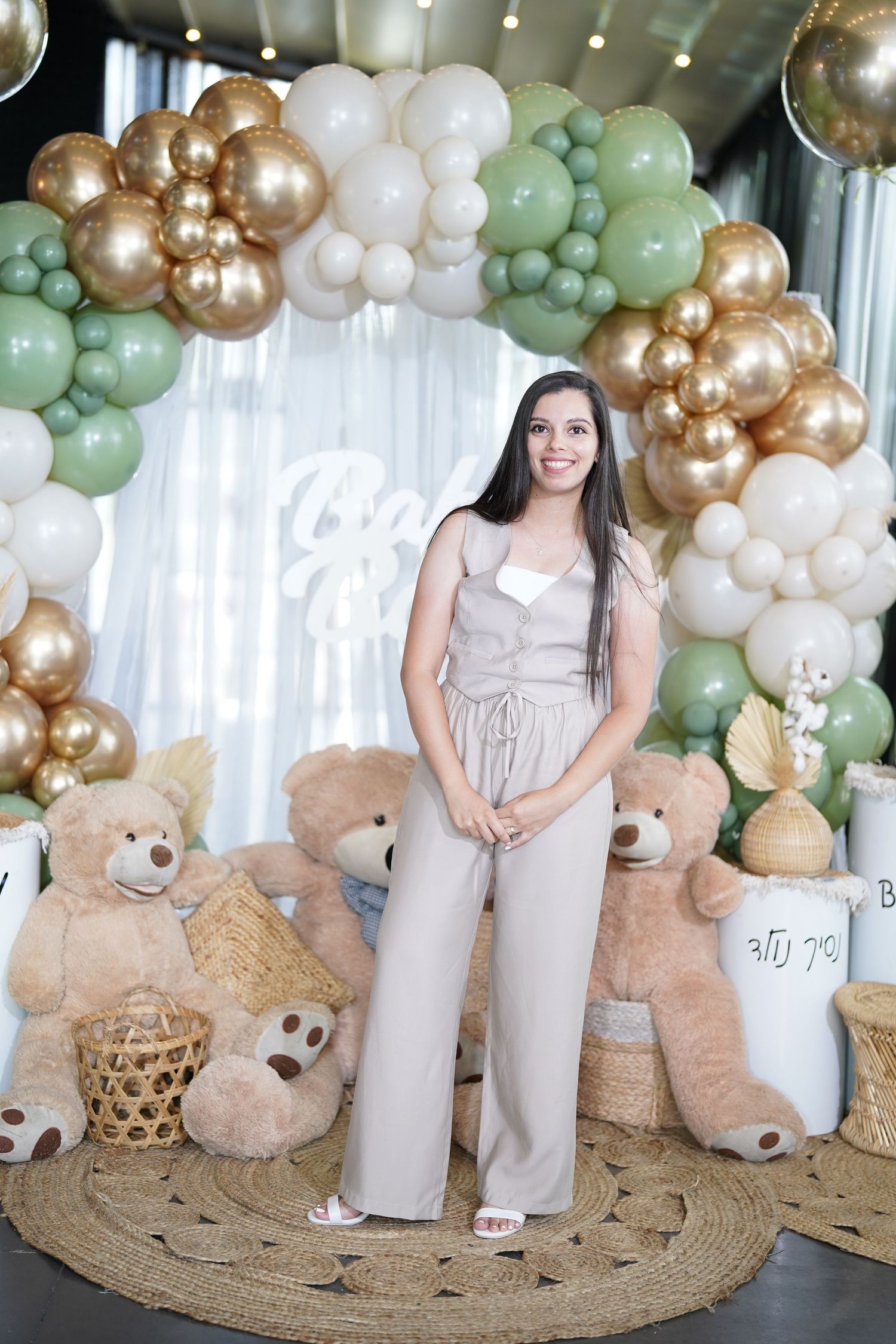 Baby shower decor featuring balloon arch, teddy bears and circular jute rug.