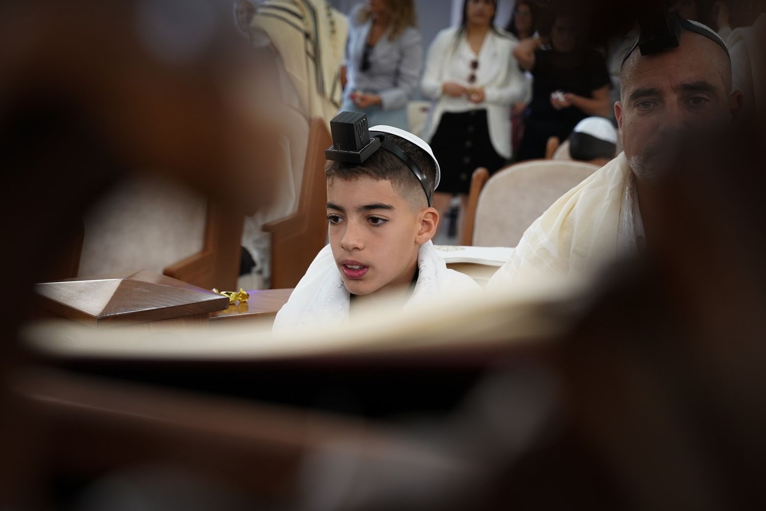 People wearing kippas and white clothing engaged in study at tables.