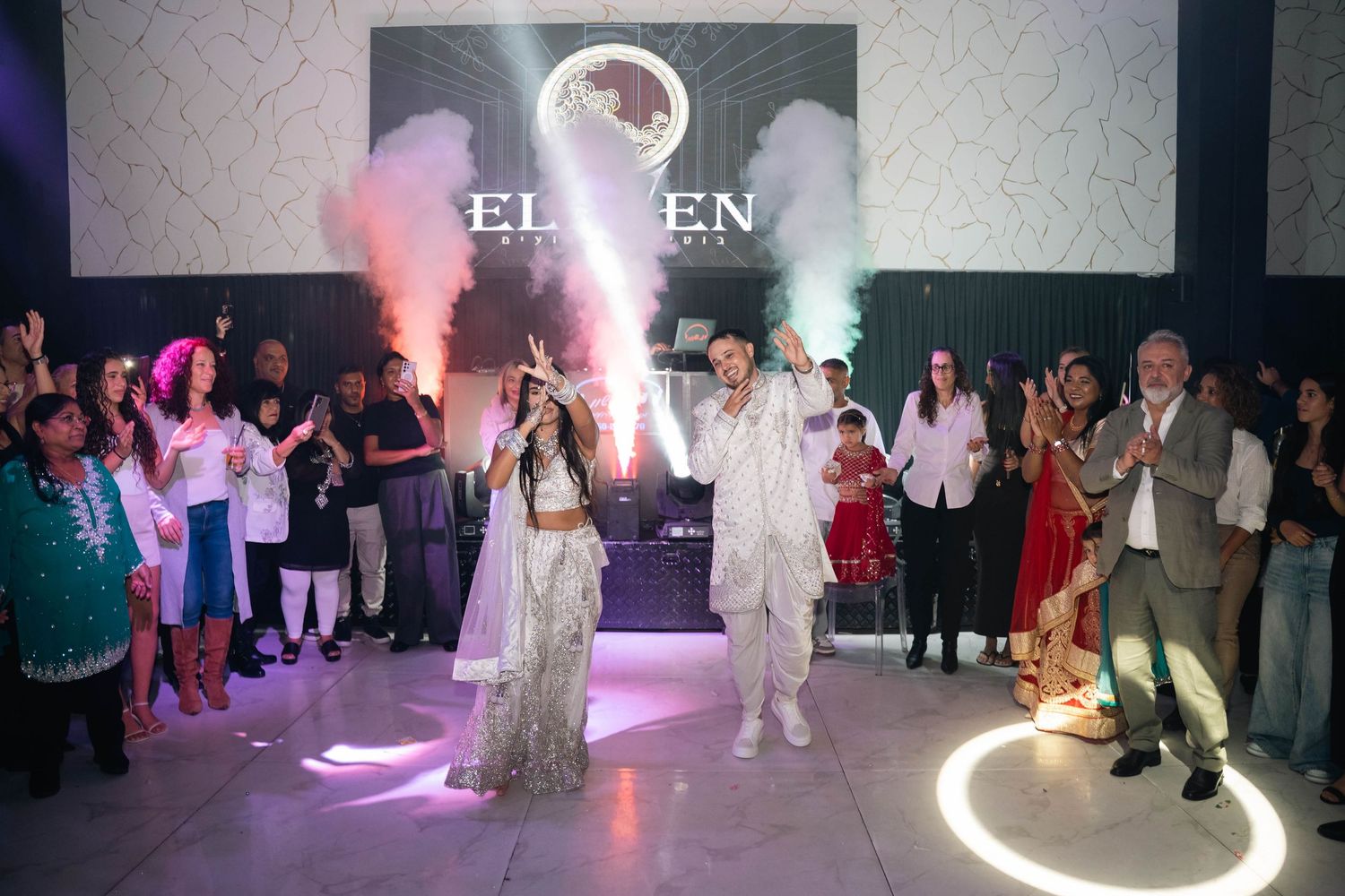 Wedding party dancing under dramatic purple and white lighting effects.