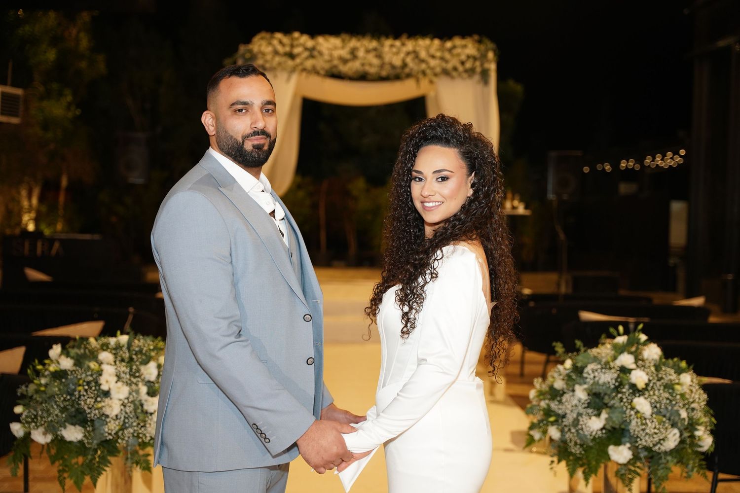 Wedding venue decorated with white floral arrangements and ambient lighting.
