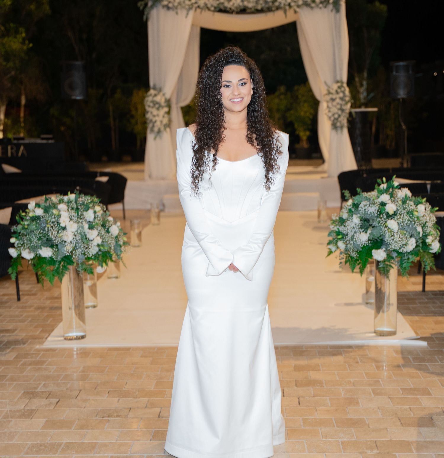 Wedding venue decorated with elegant white draping and greenery floral arrangements.