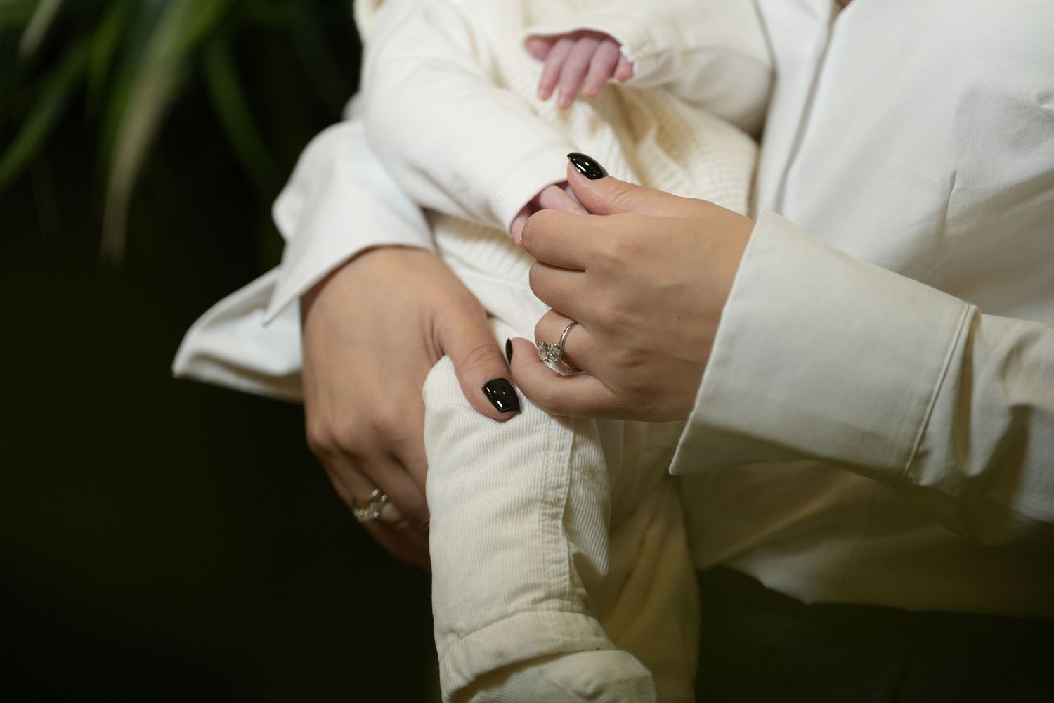 Close-up sequence of hands in white sleeves holding and examining a small white object against a dark background.