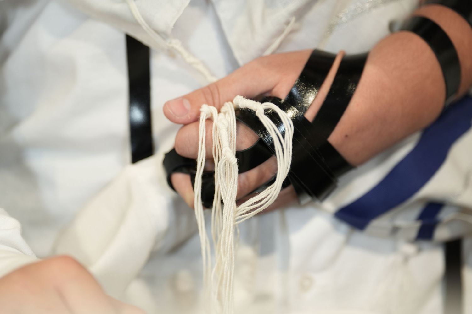 A sequence of photos showing hands pulling and stretching fresh pasta dough into long noodles on a white surface.