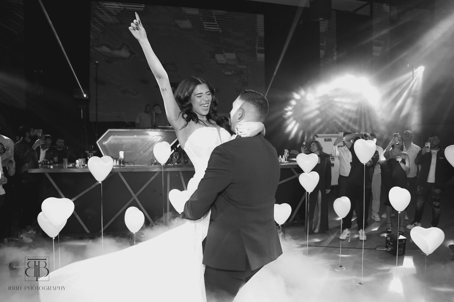 A couple dancing at their wedding reception surrounded by illuminated heart decorations.