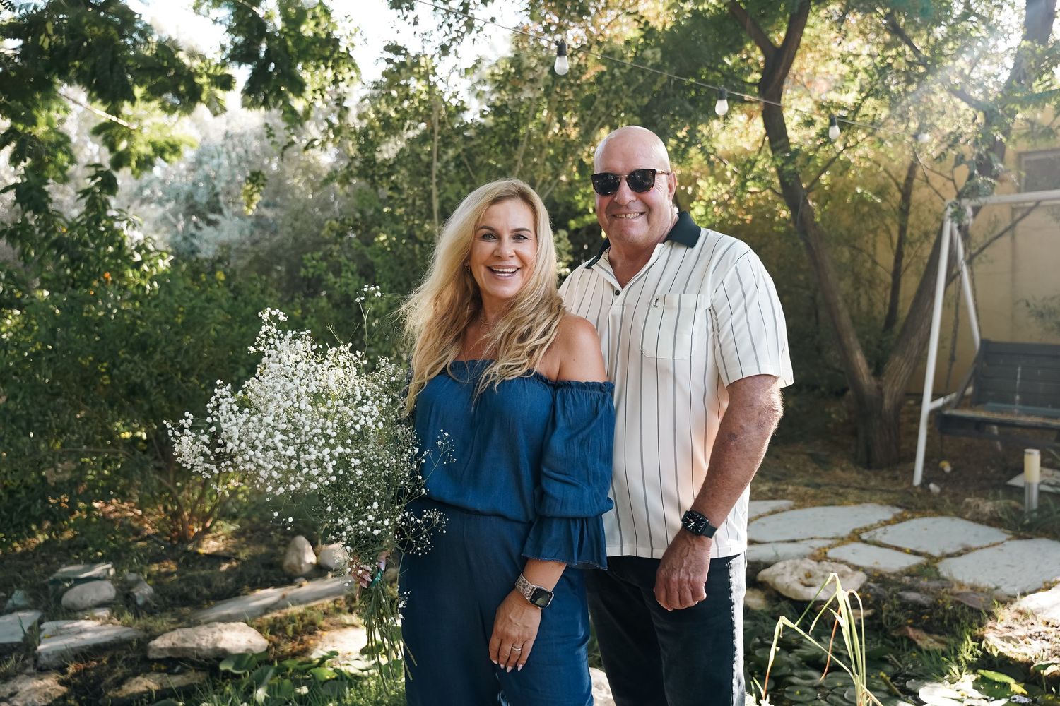 Couple embraces in a romantic outdoor garden setting during golden hour.
