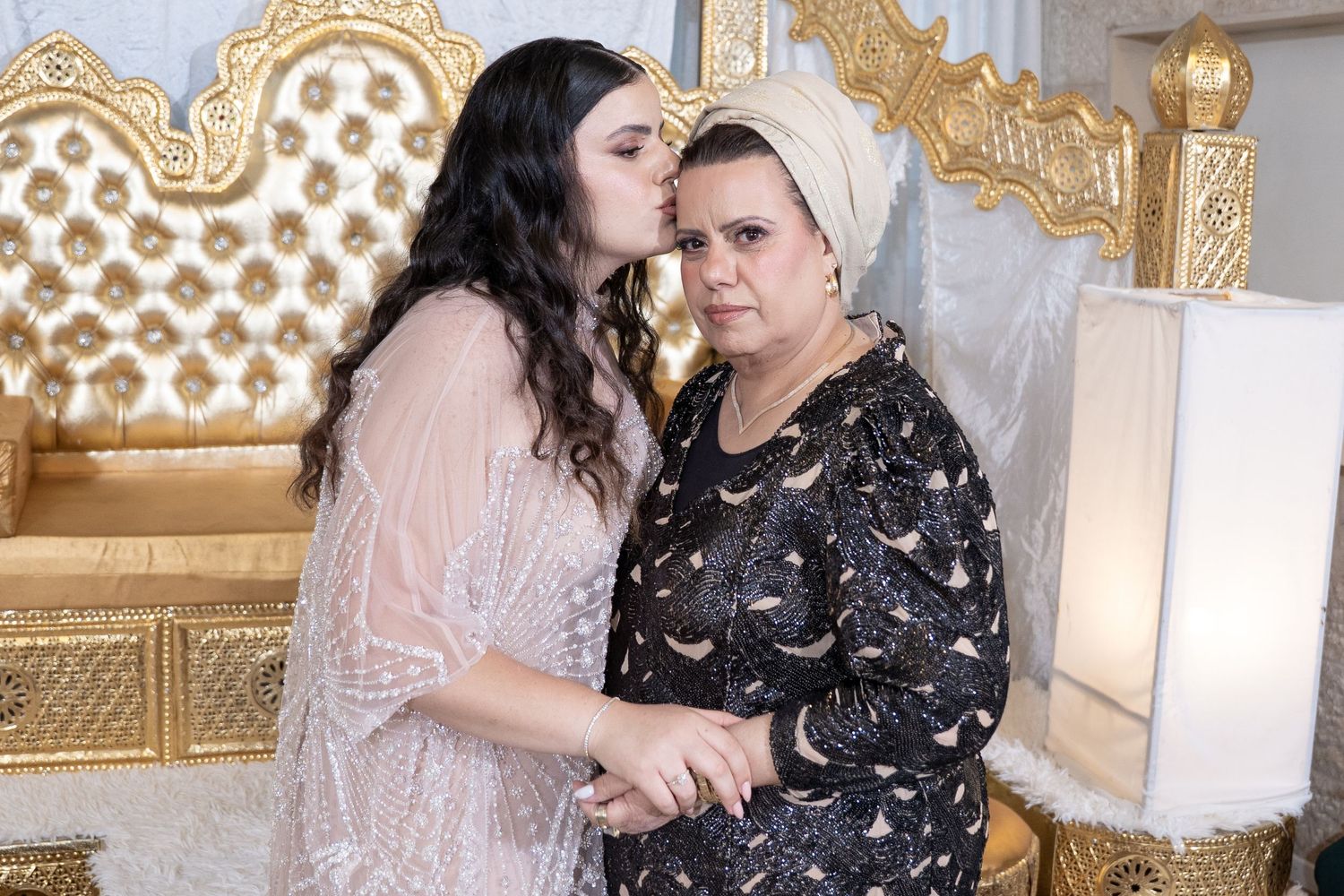 Two people in intimate pose against ornate gold throne backdrop.