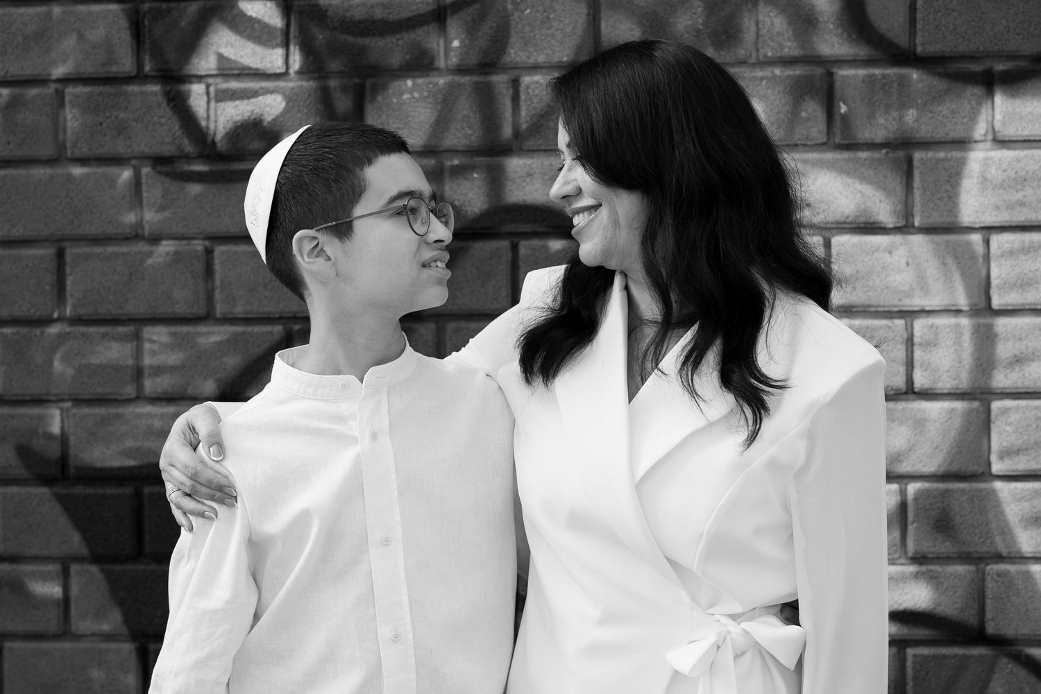 Black and white portrait series against brick wall with artistic composition.