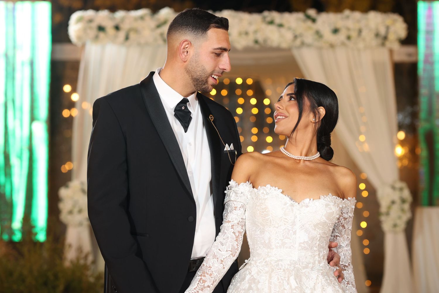 Luxurious wedding venue decorated with white flowers and sheer curtains against a romantic backdrop.