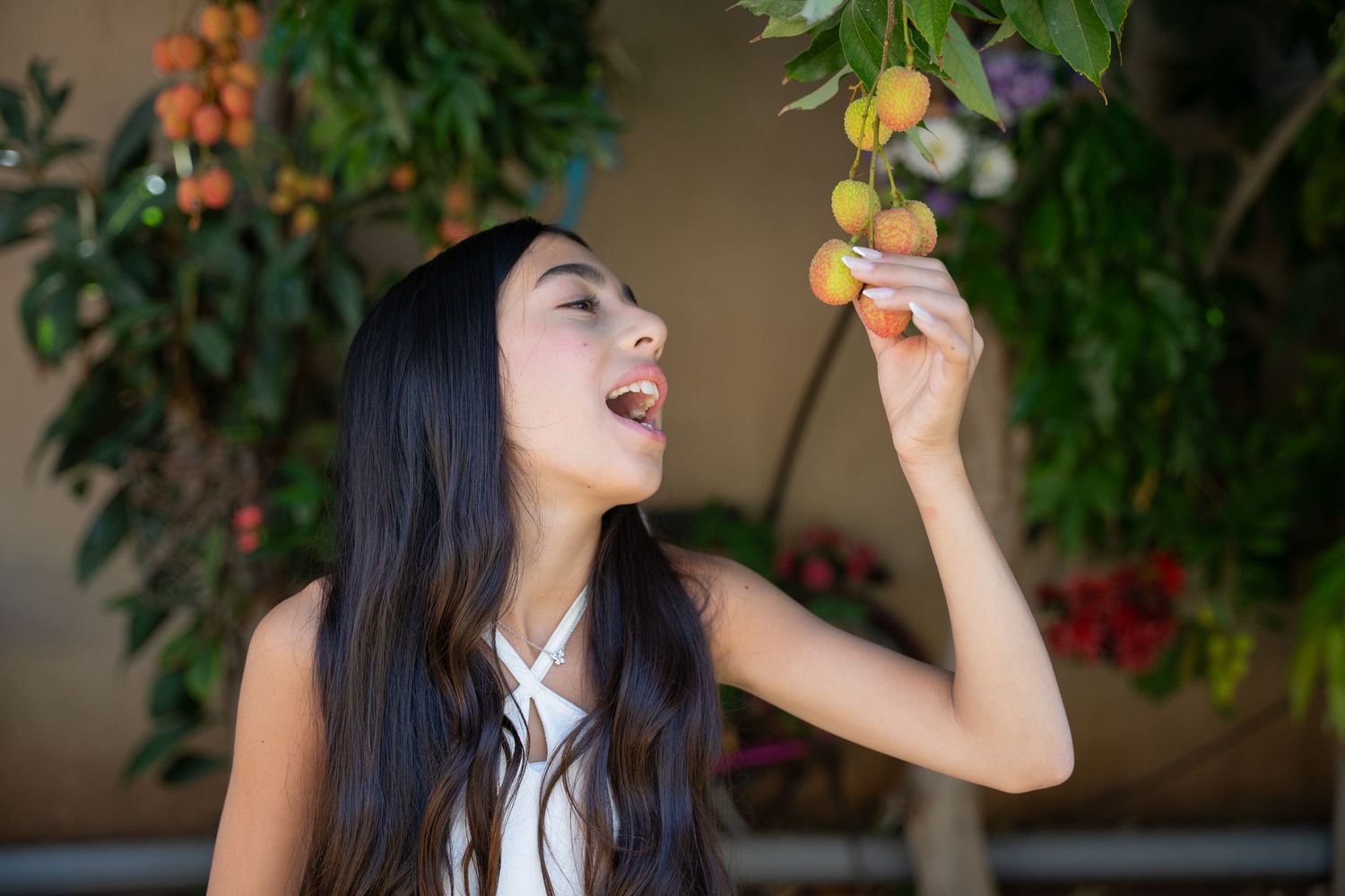 Playful garden photo session featuring white dress and fruit trees.
