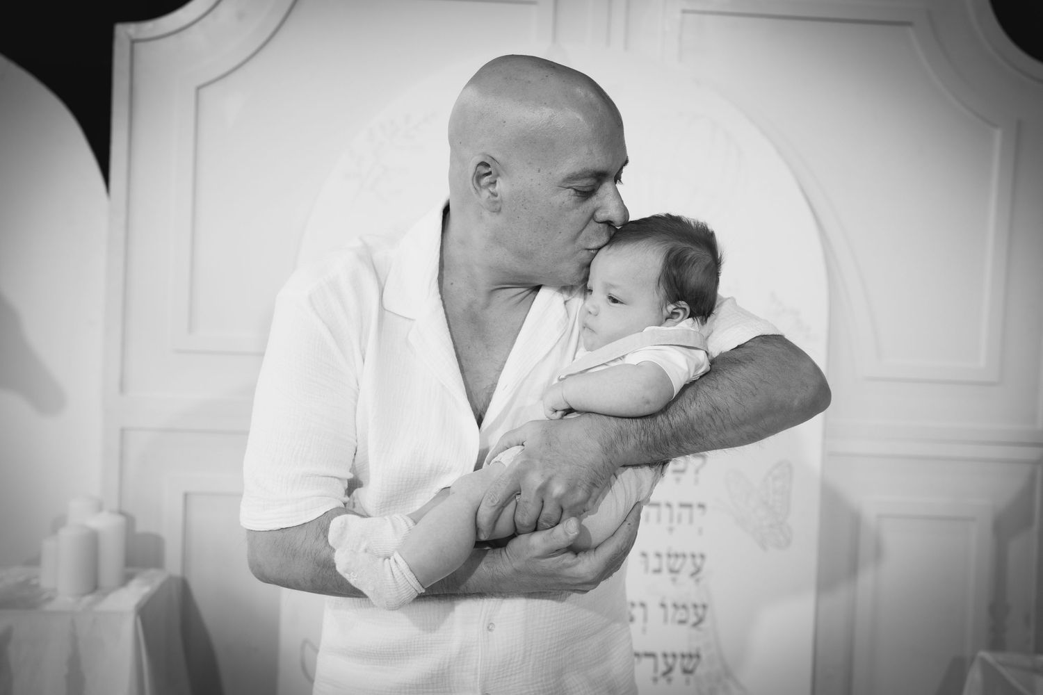 Black and white photo series showing tender family moments in a studio setting with soft lighting.