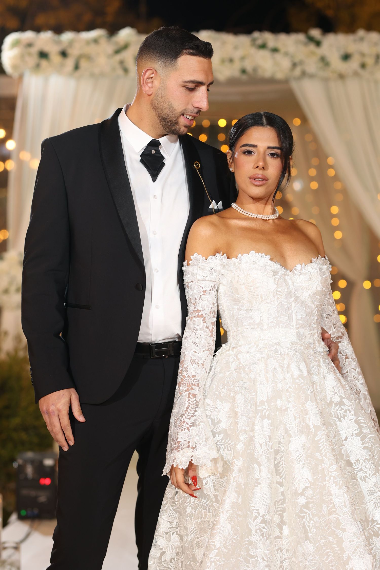 Formal wedding attire featuring a classic black tuxedo and an ornate white lace gown.