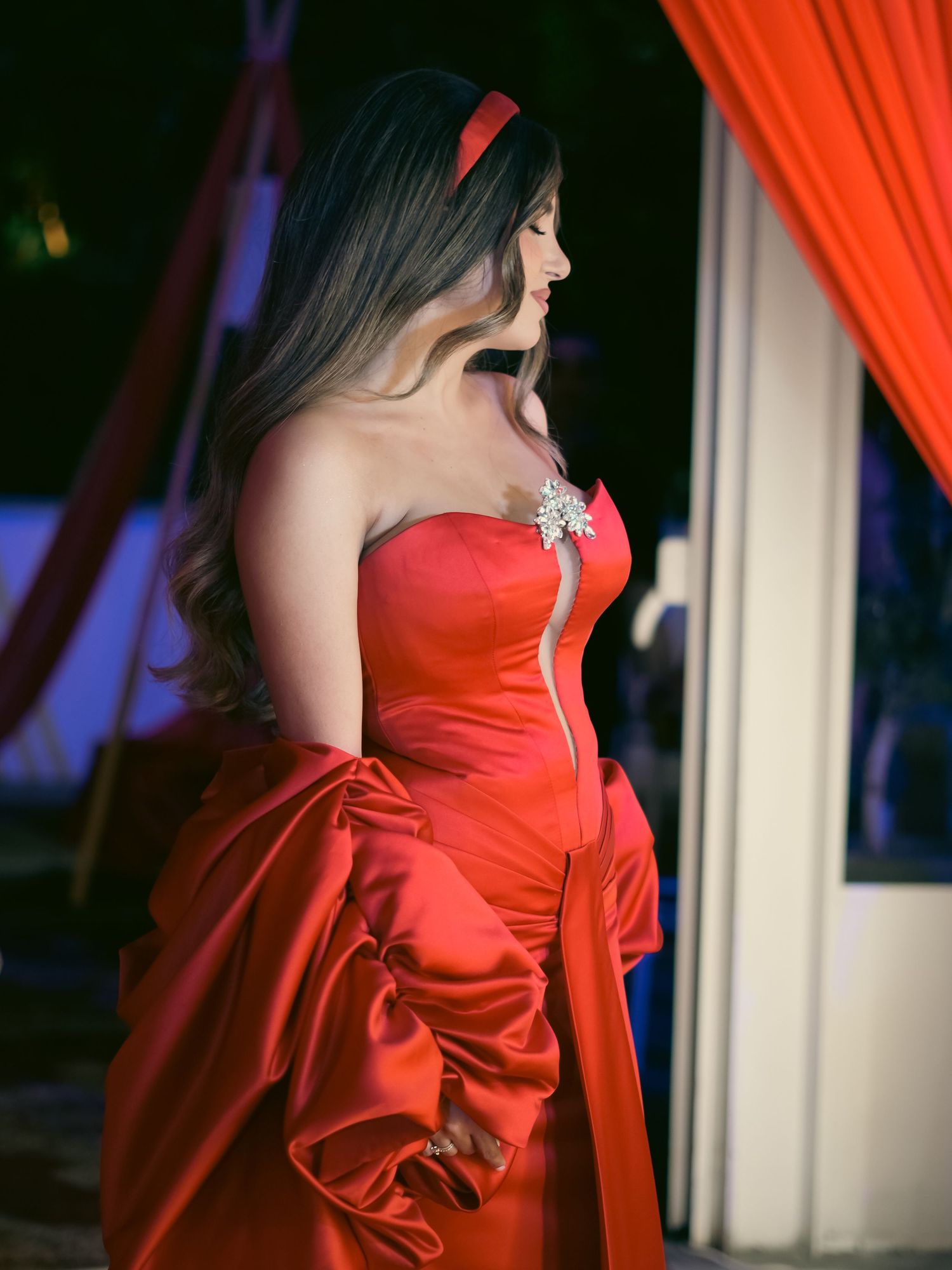 Fashion editorial series featuring vibrant red evening gown against dark backdrop.