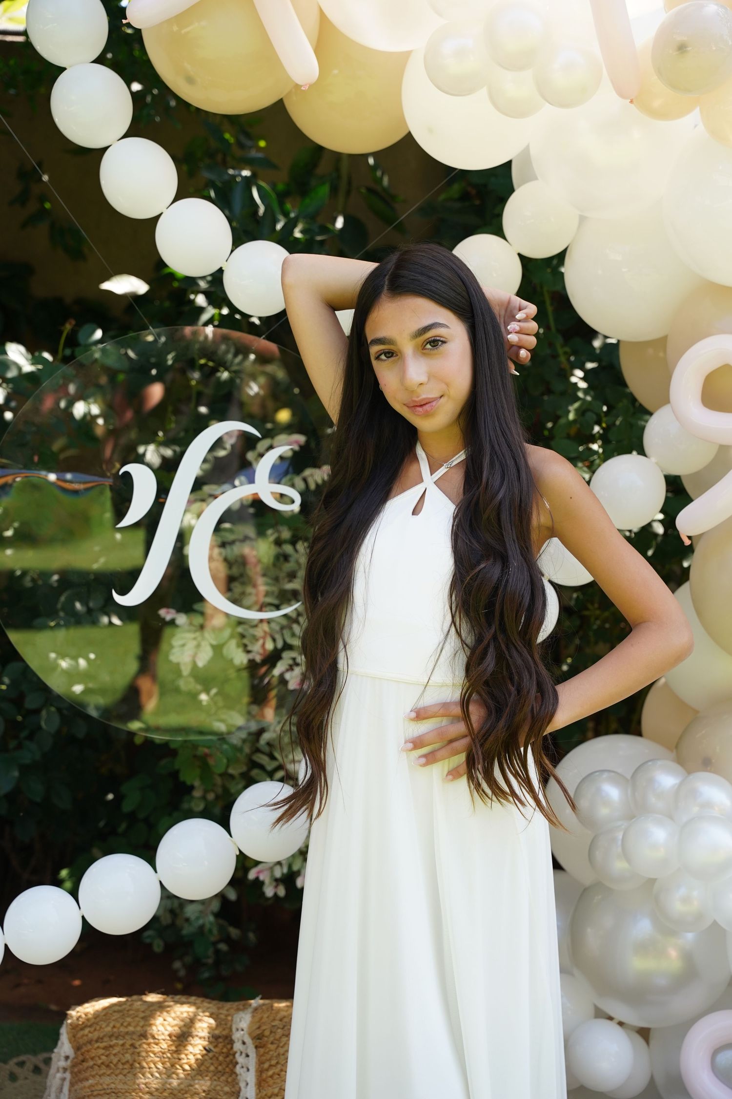 White balloon arch installation with elegant dress photoshoot in garden setting.