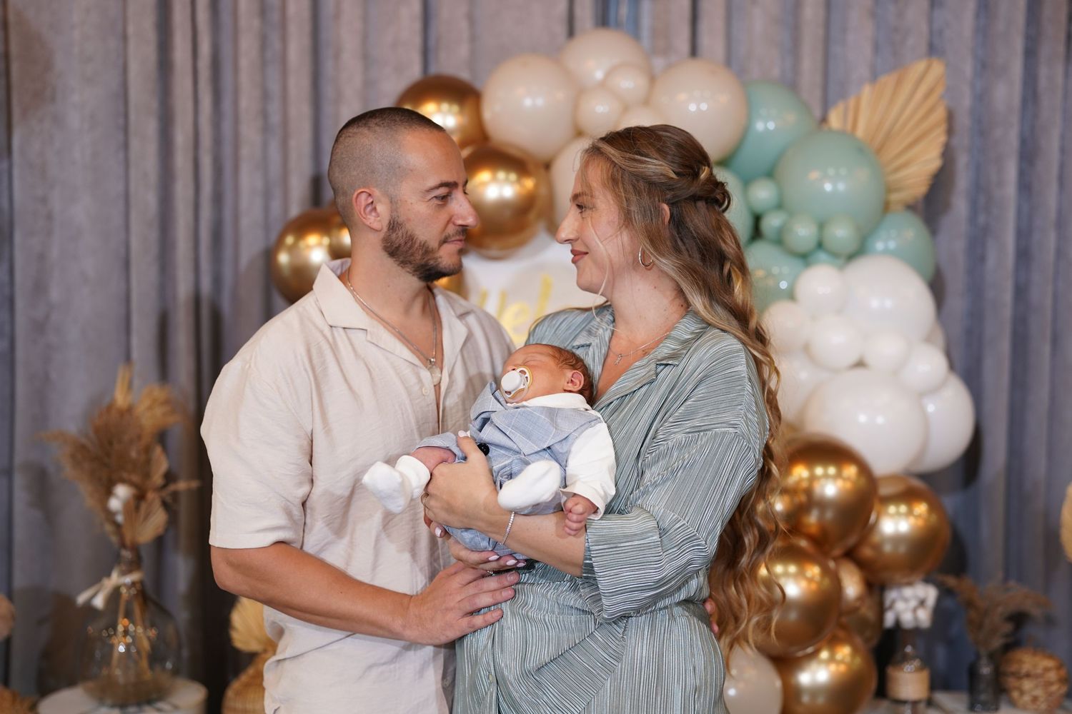 Loving moment captured at a baby shower with mint and gold balloon backdrop.