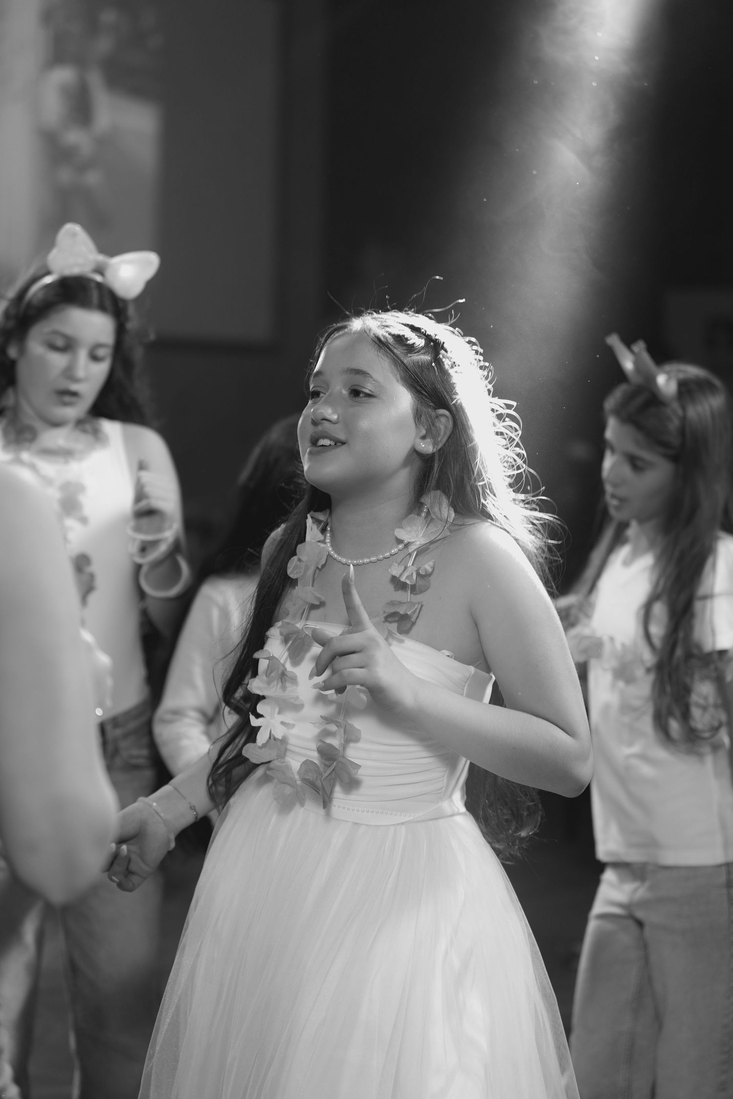 A series of black and white photos showing people in white dresses dancing and celebrating at what appears to be a wedding reception.