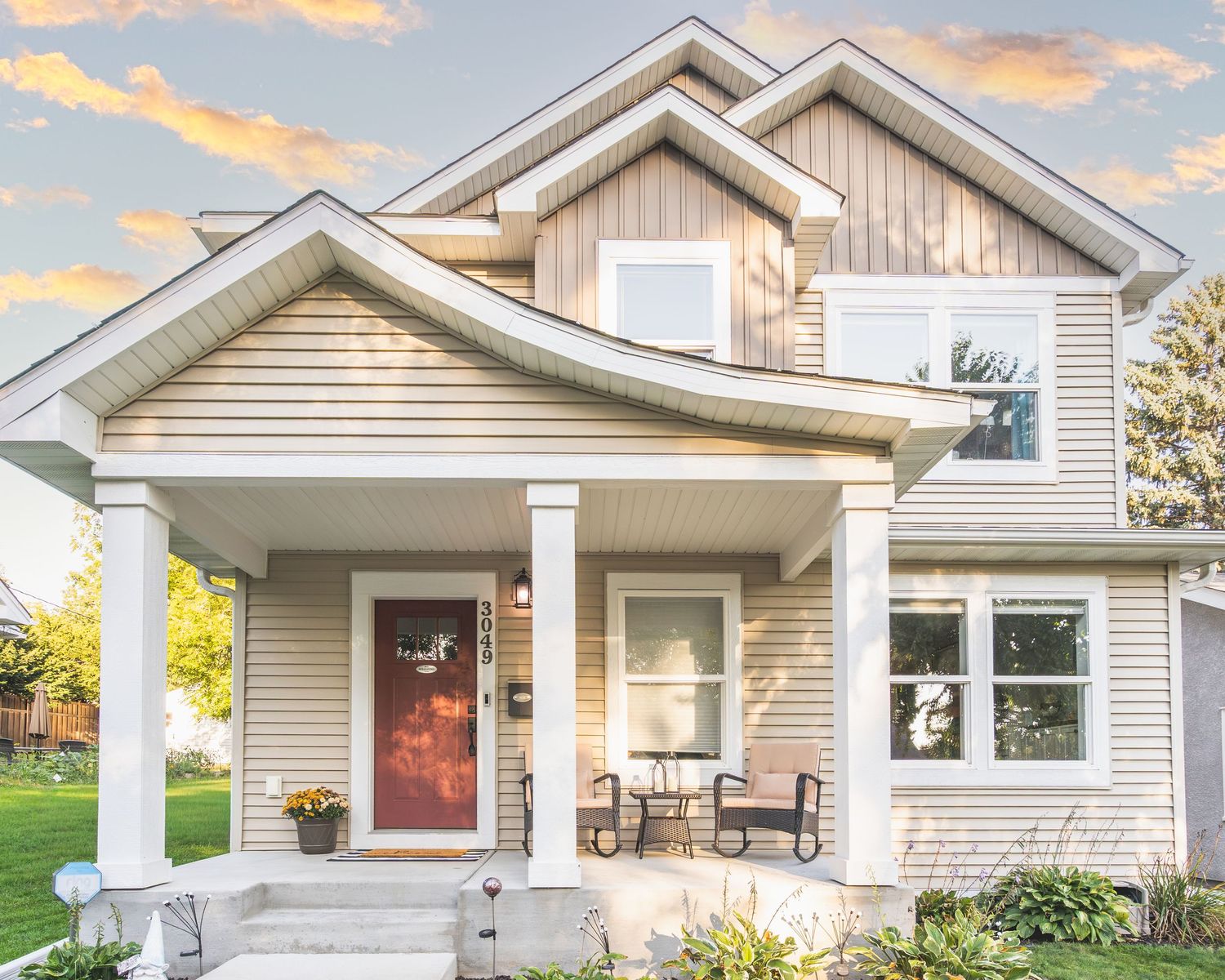 A series of modern craftsman-style homes with white siding and covered front porches at sunset.