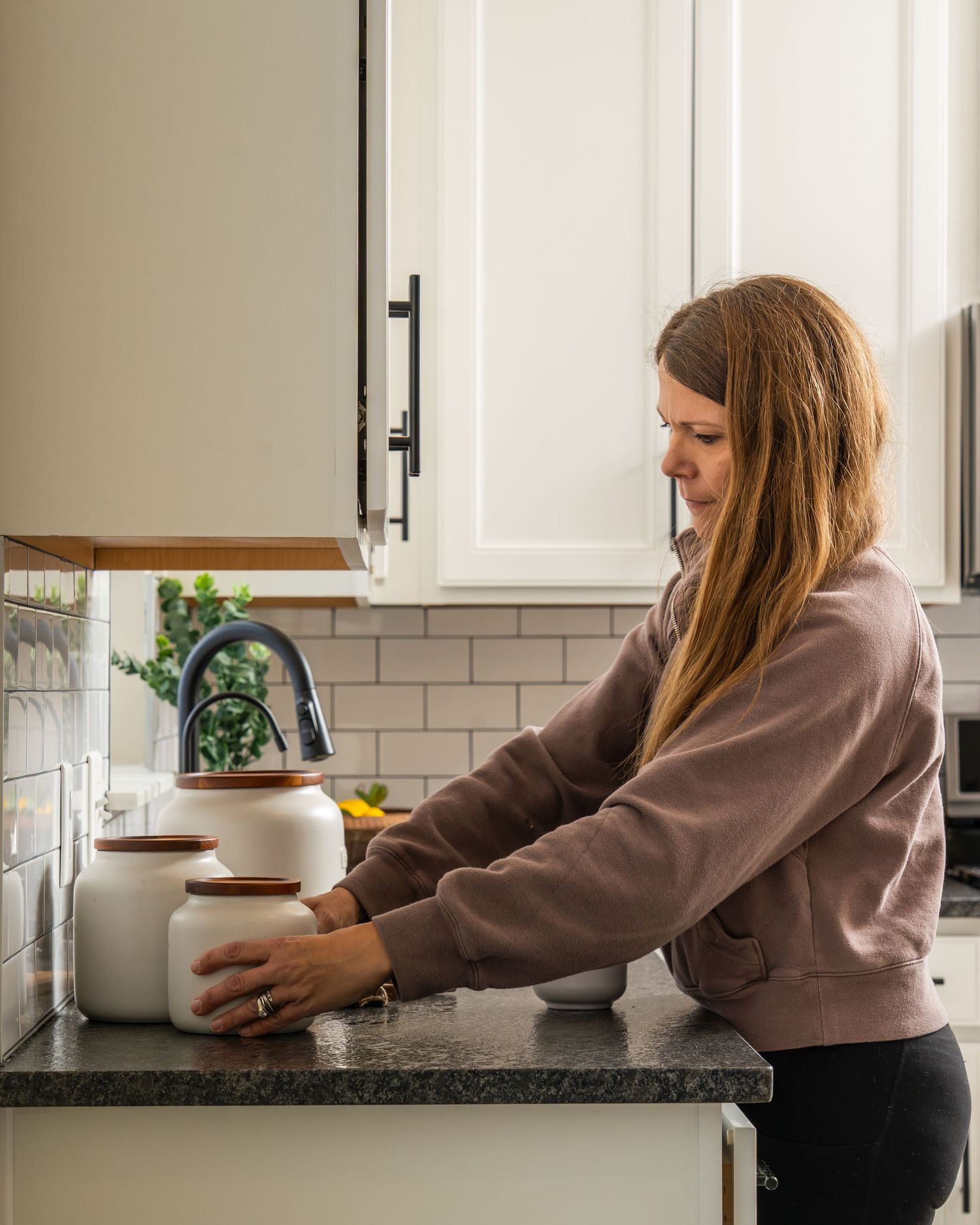 A sequence showing someone reaching and moving across a white kitchen counter with subway tile backsplash.