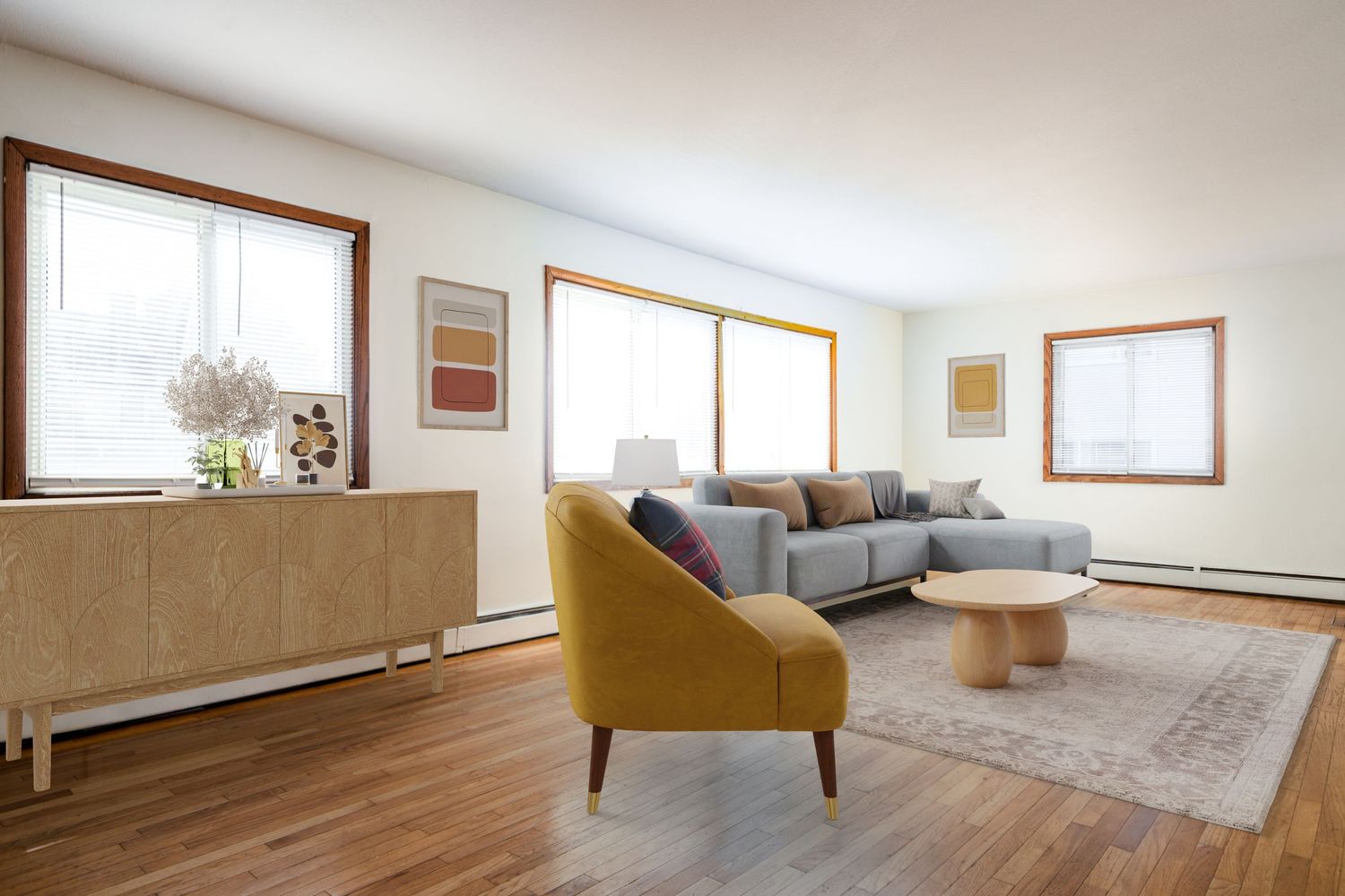 Modern living room with grey sectional sofa, mustard accent chair, light wood furniture and multiple windows.