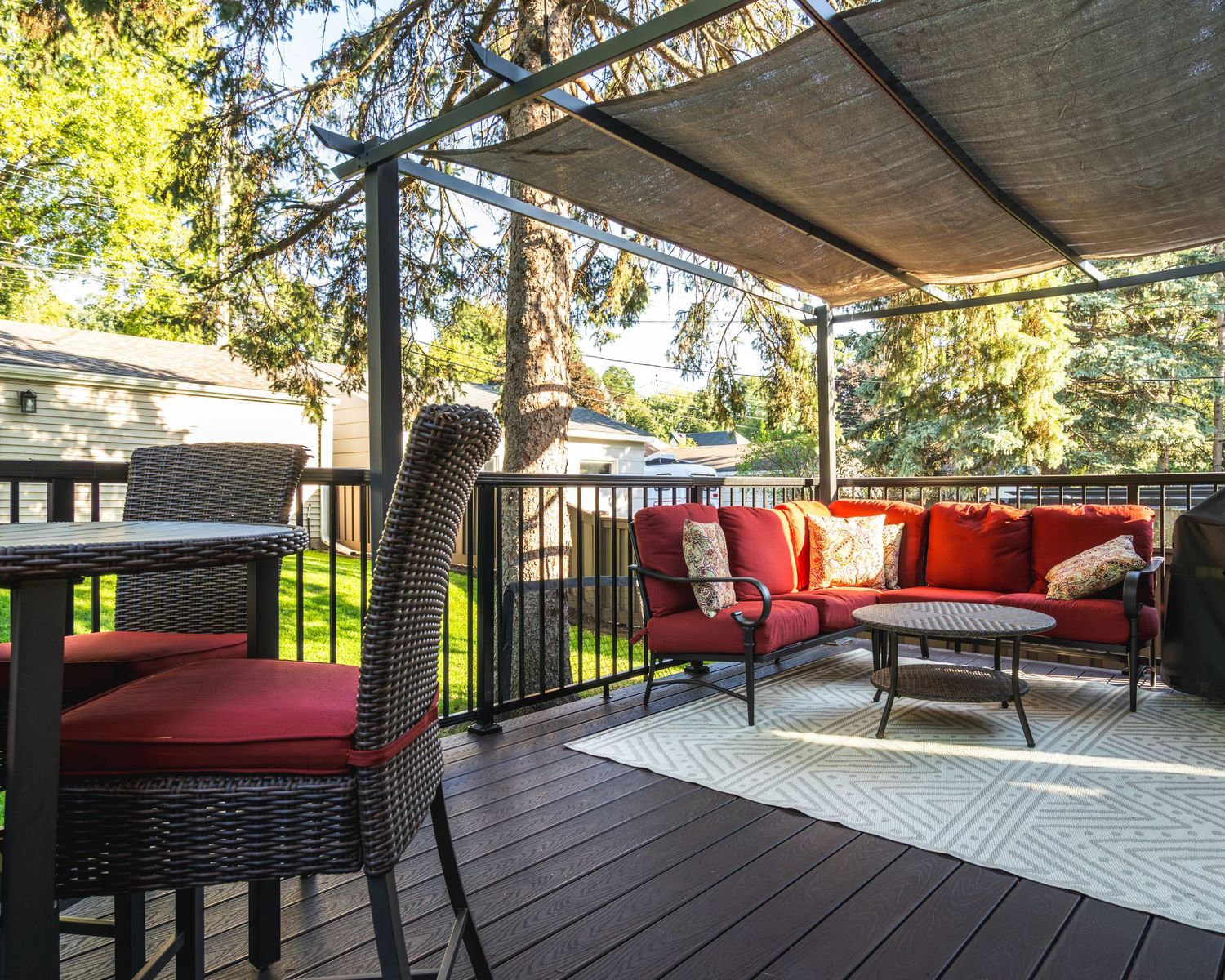 Panoramic view of a modern deck with comfortable outdoor furniture and shade coverings overlooking a scenic landscape.