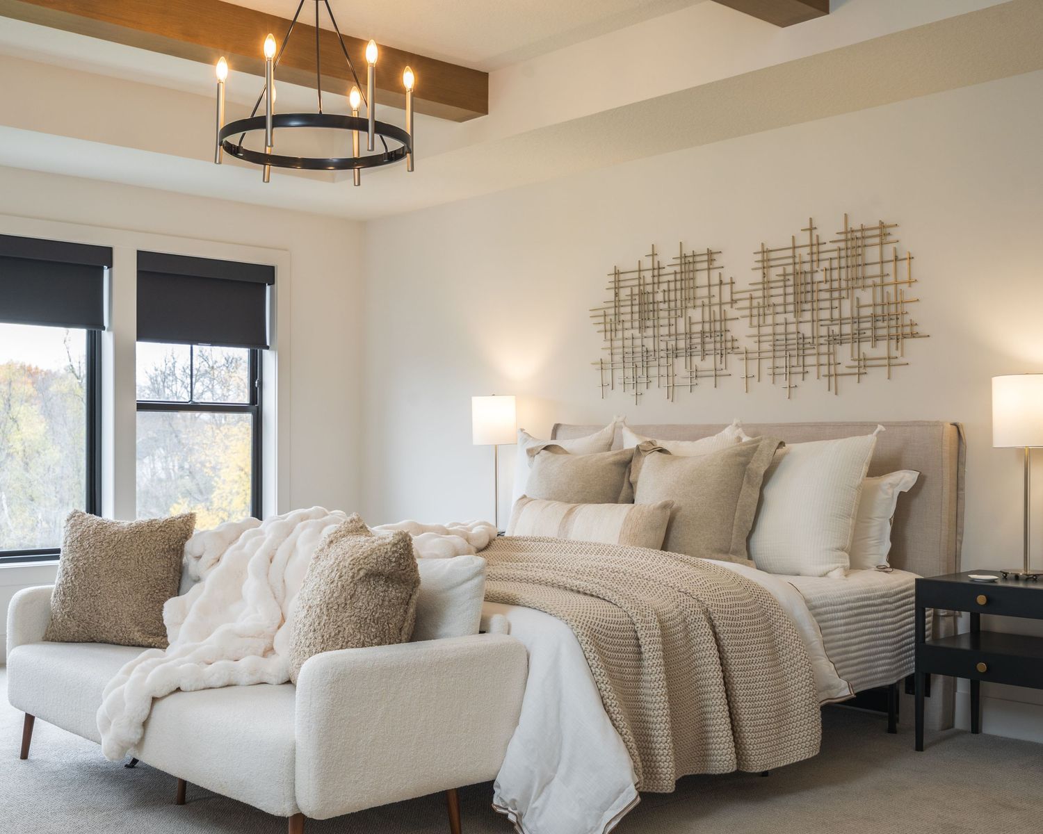 Modern bedroom interior with exposed wooden beams, circular chandelier, and neutral color scheme featuring white bedding.