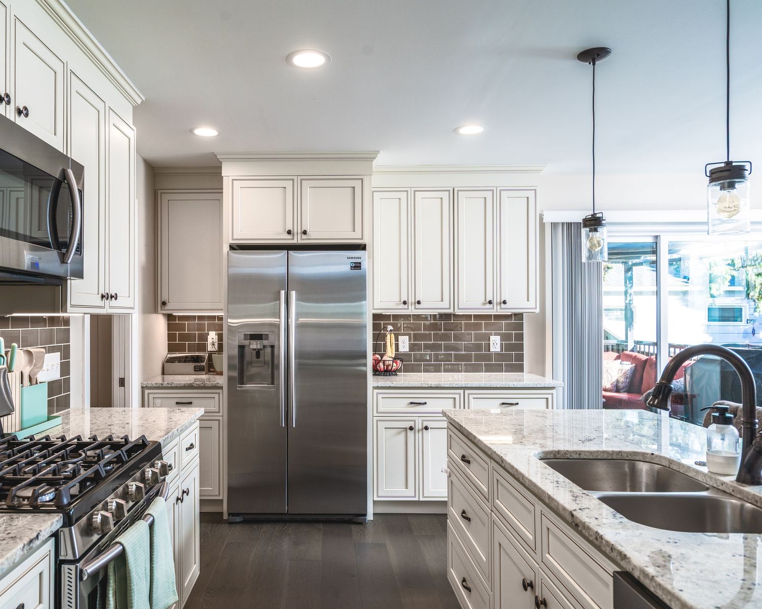 Modern white kitchen with stainless steel appliances, granite countertops, and recessed lighting in open concept layout.