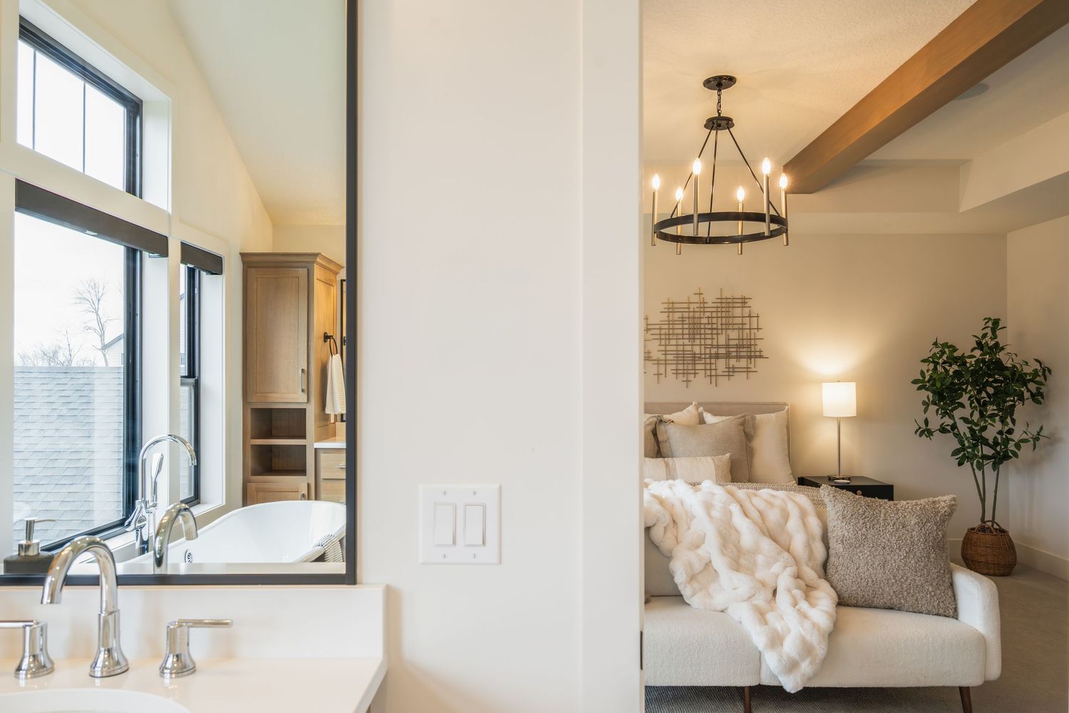 Modern farmhouse bedroom features a circular black chandelier, white bedding, and exposed wooden beams.