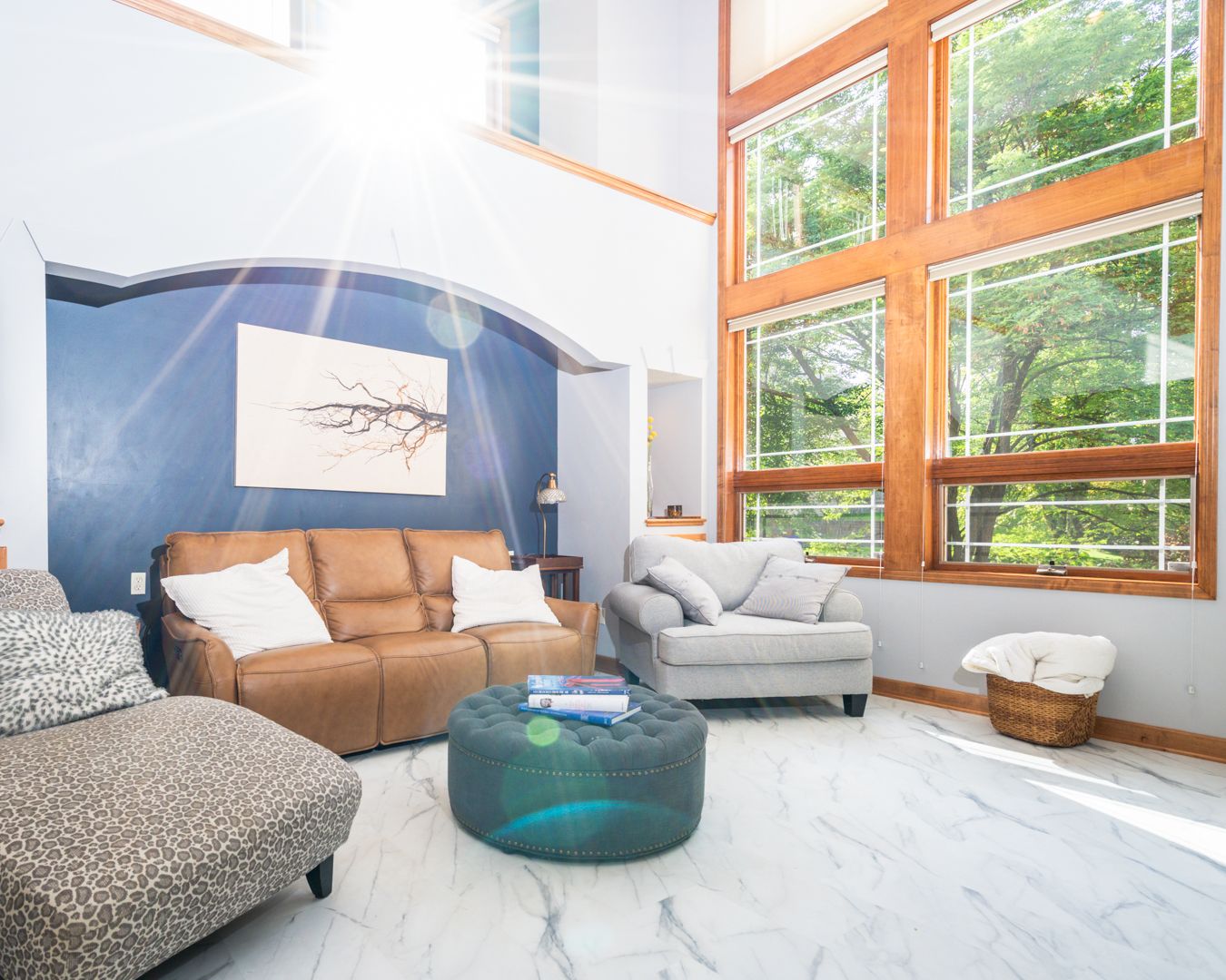 Modern living room features tall windows with orange frames, gray couch and white minimalist interior design elements.