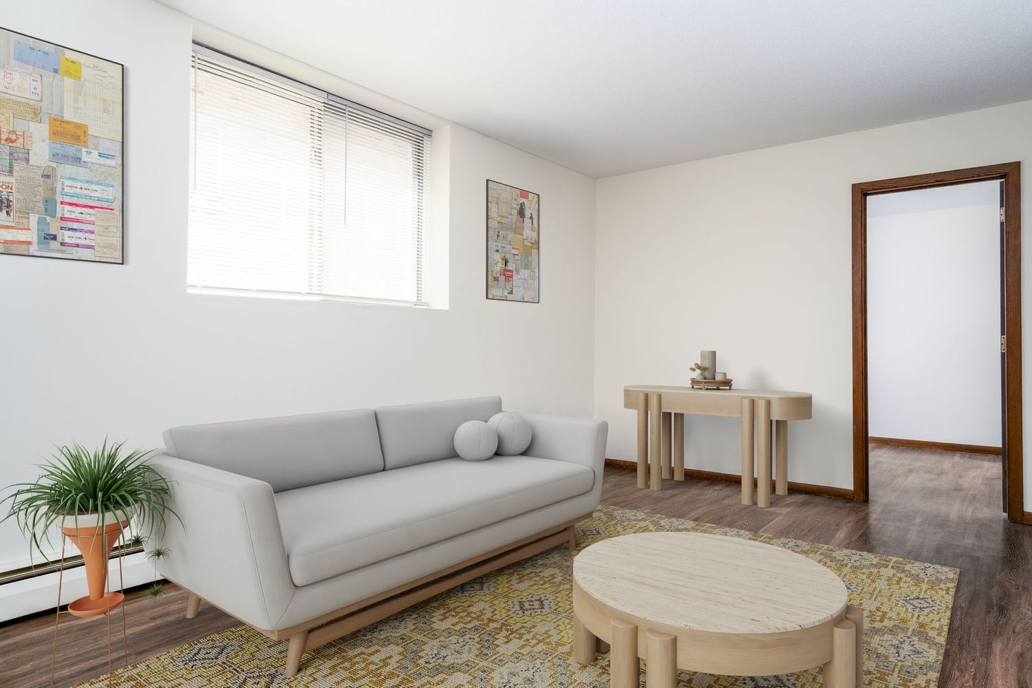 Modern living room interior with gray sofa, round coffee table, vintage rug and potted plant by window.