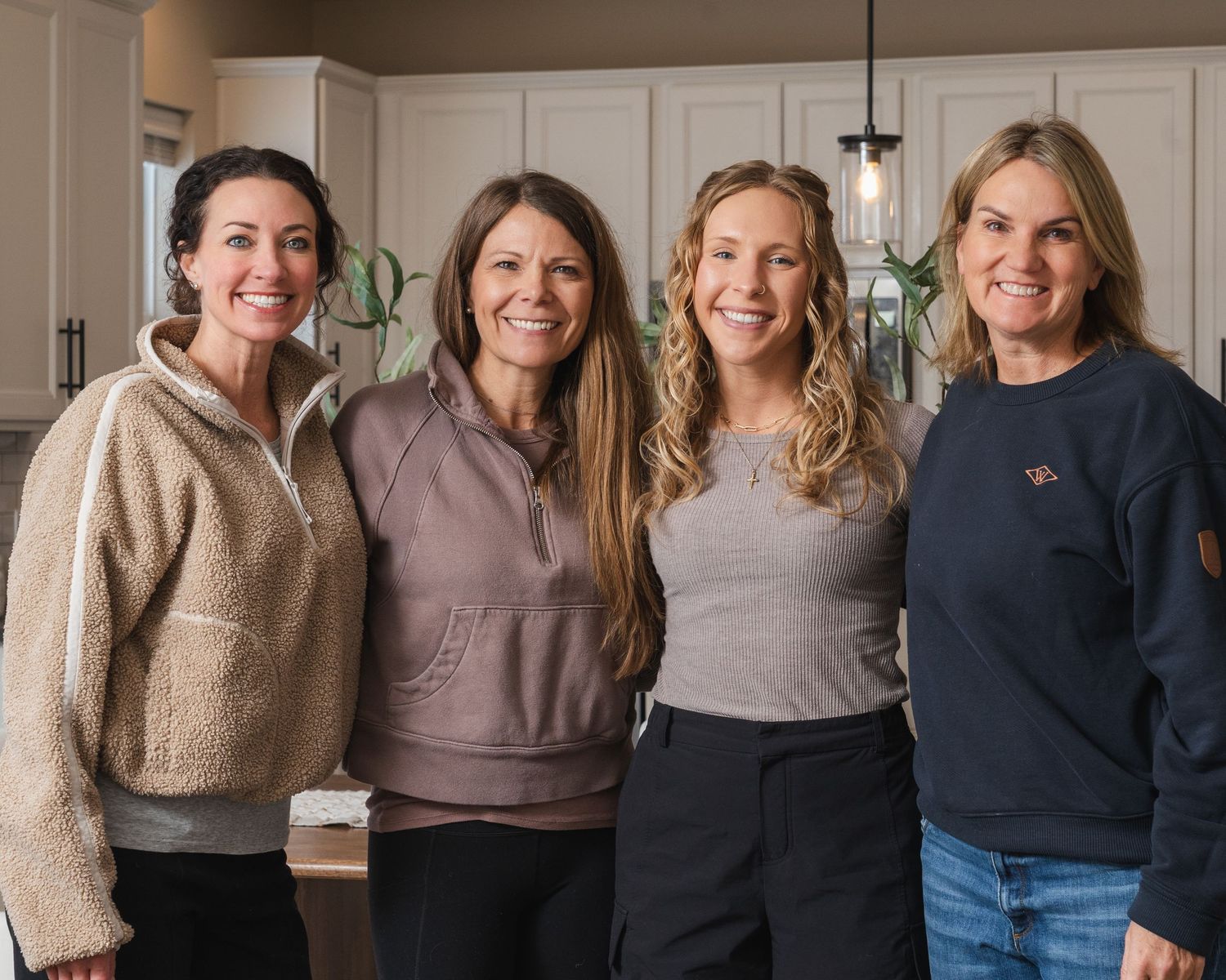 A group of people standing together wearing casual sweaters and jeans in an indoor setting.