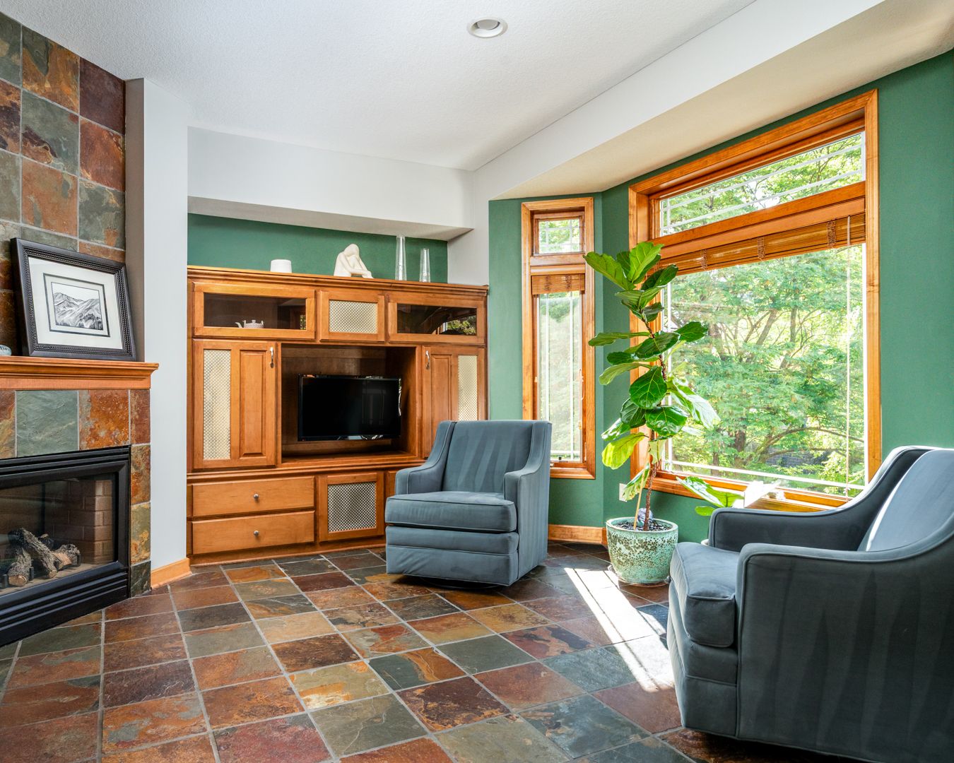 Gorgeous brown tiled flooring stretches across a bright modern living room with large windows and wood trim accents.