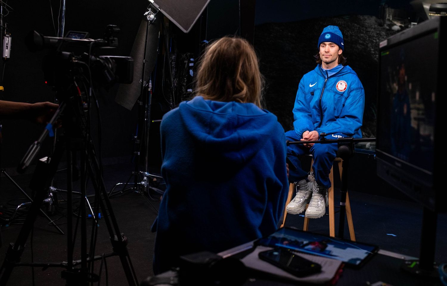Interview setup with camera equipment and lighting in dark studio setting.