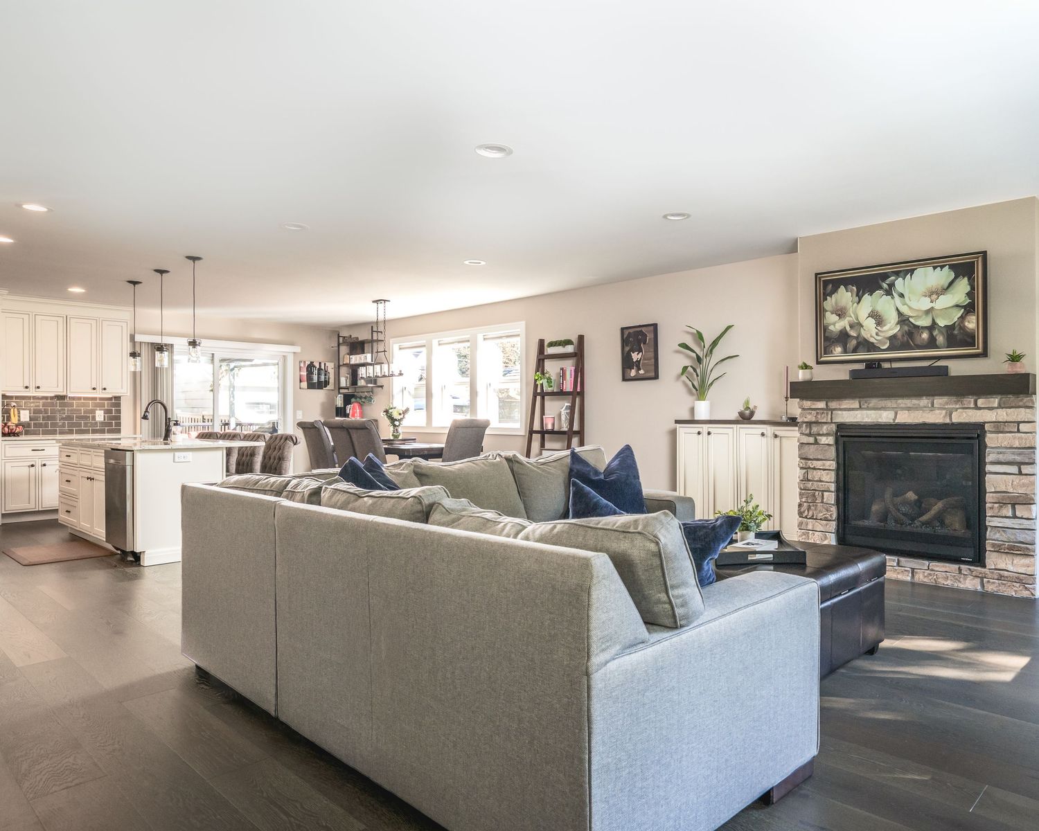 A modern living room with light grey sectional sofa and open concept layout features bright natural lighting.