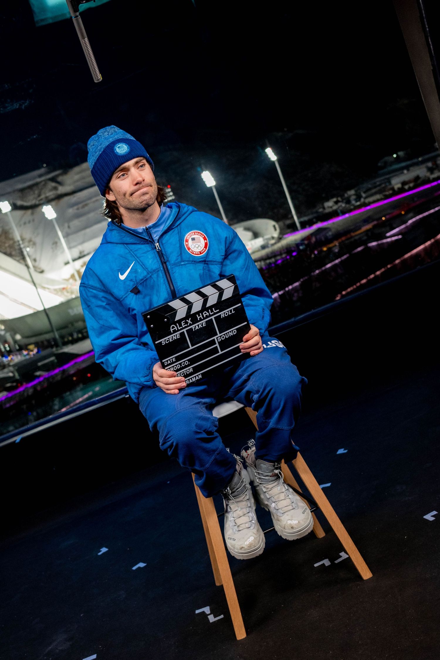Olympic athlete holding film slate while seated during interview.