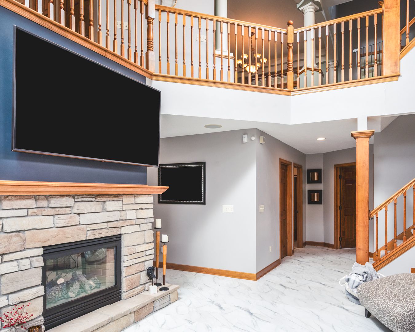 Modern gas fireplace with white brick surround and mounted TV in an open concept living room with wood stairs.