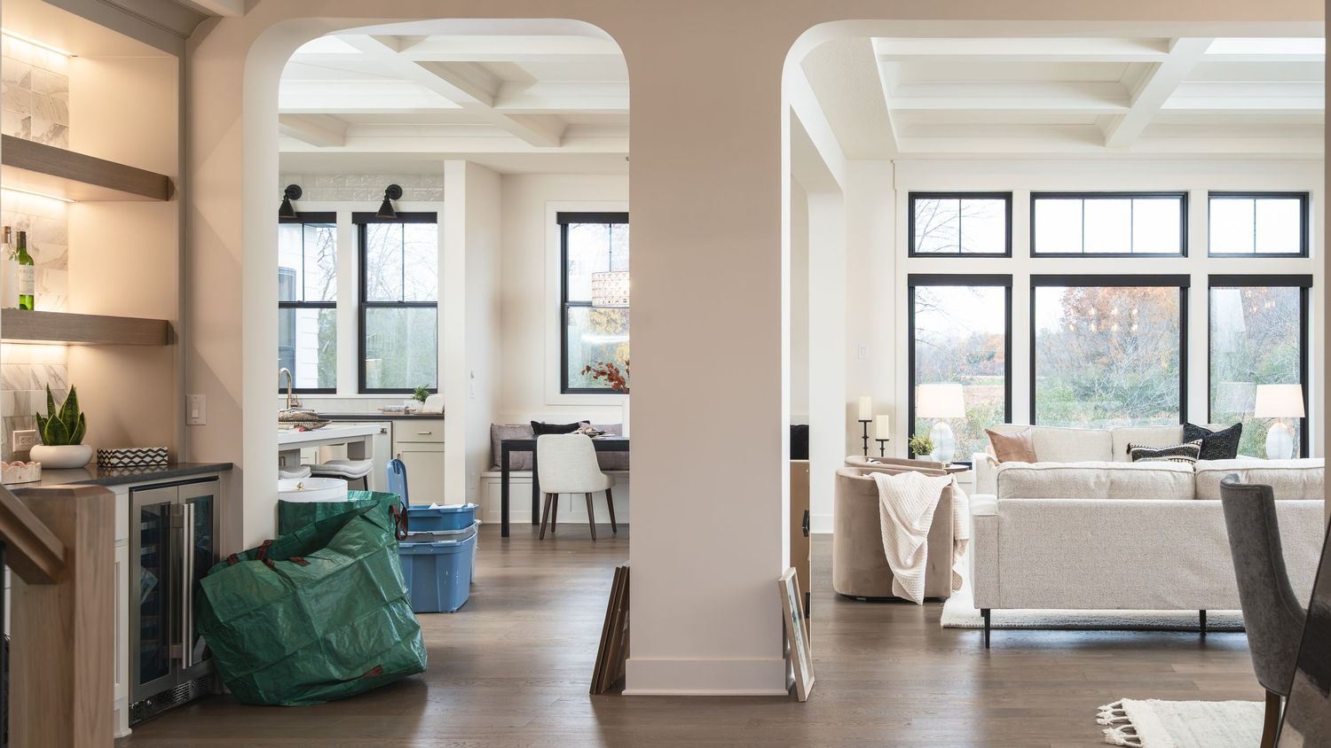 A modern open concept office space with white walls, large windows, and minimalist furniture arranged throughout.