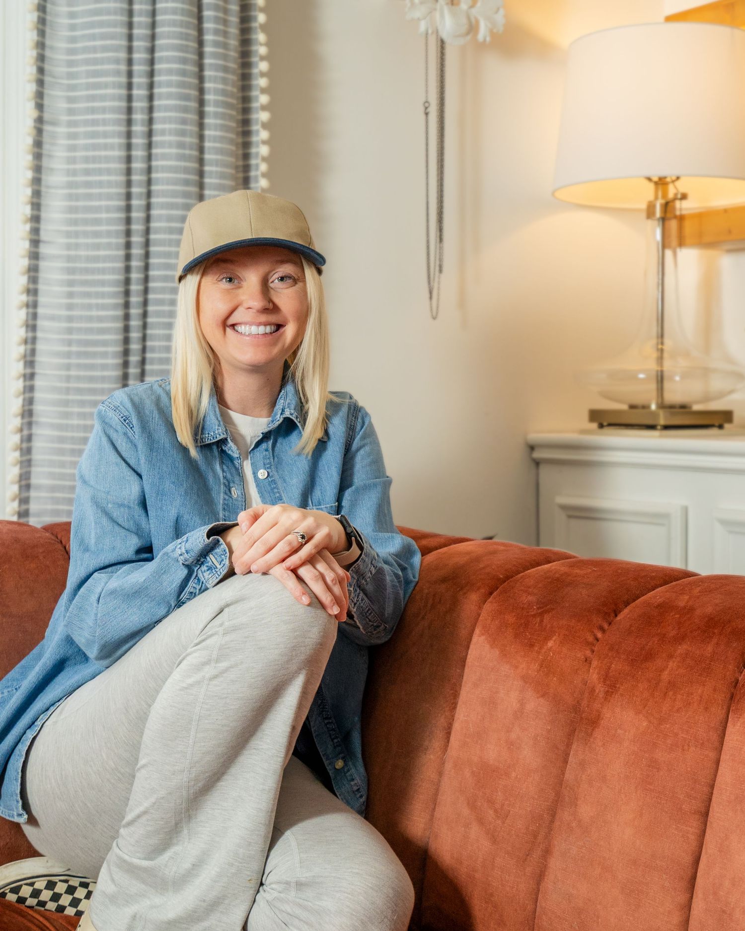 Casual portrait series of someone in denim sitting on a brown velvet couch in a bright modern room.