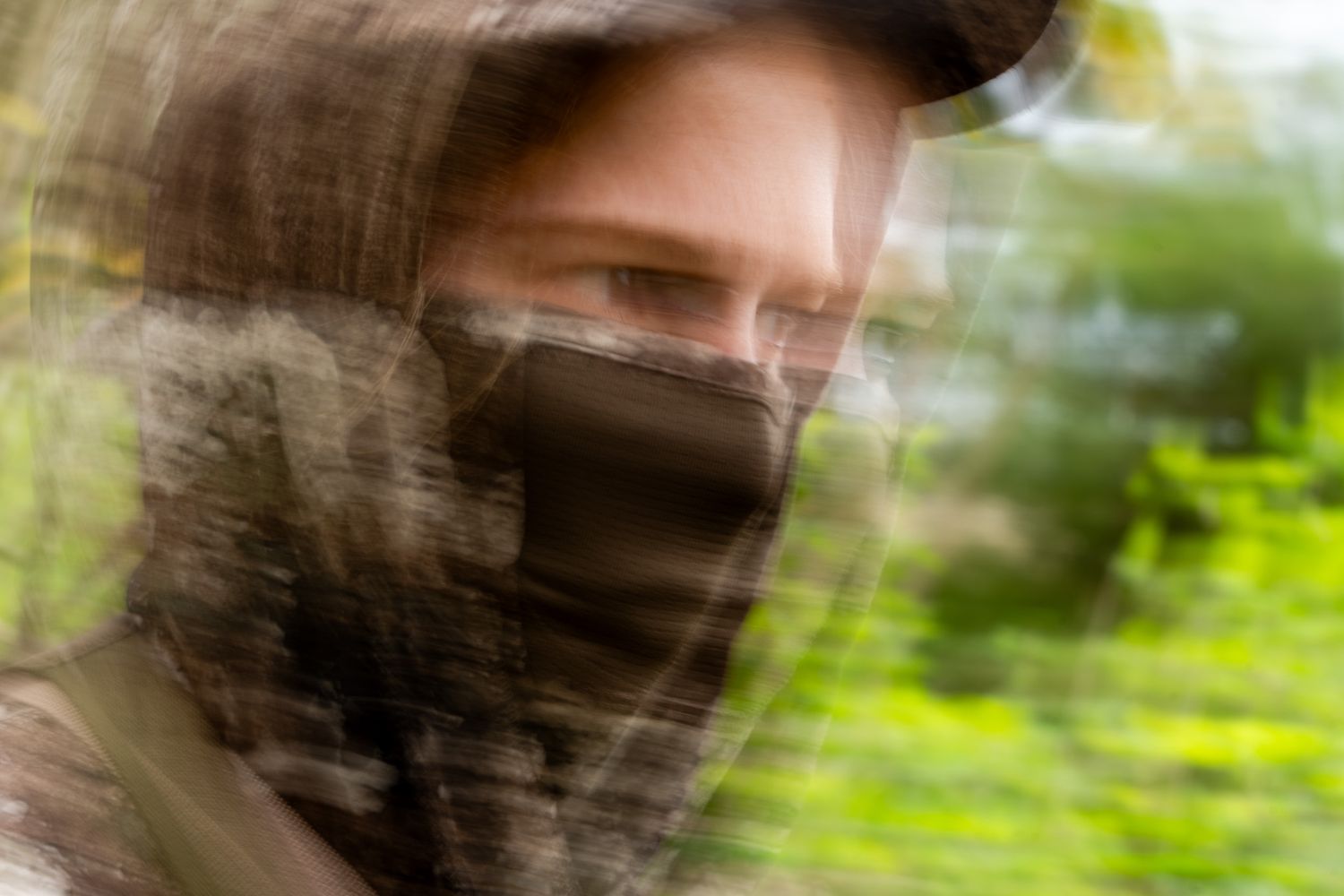 Blurred artistic photo of person in hunting gear with face covering.