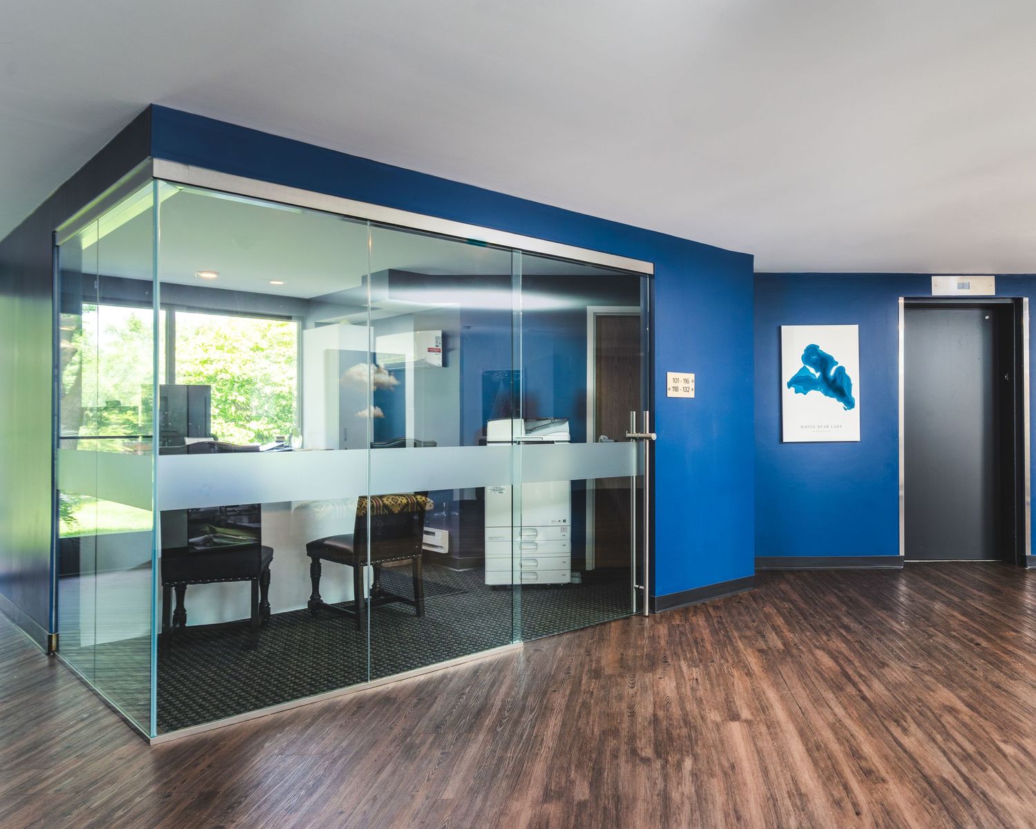 Modern office interior with hardwood floors and blue accent walls showcases an open floor plan design.